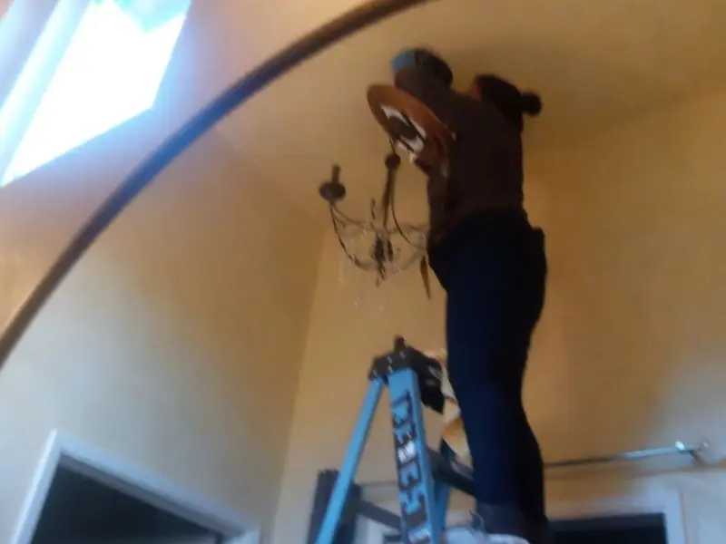 Electrician installing a chandelier in a Lompoc residence